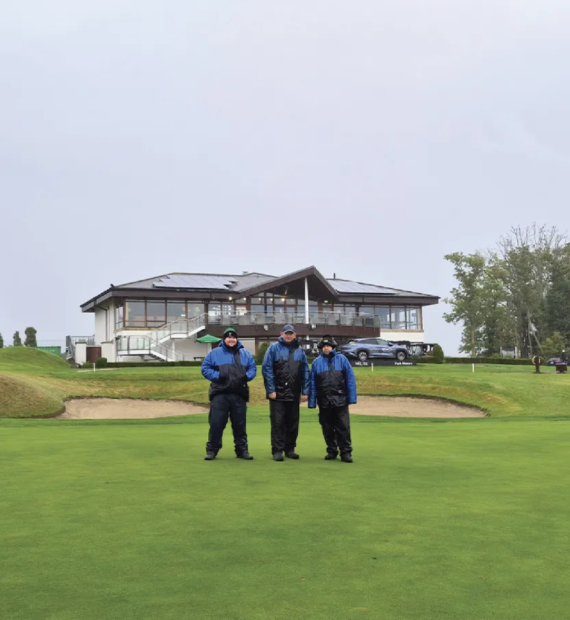 Men in working overalls in front of golfing clubhouse