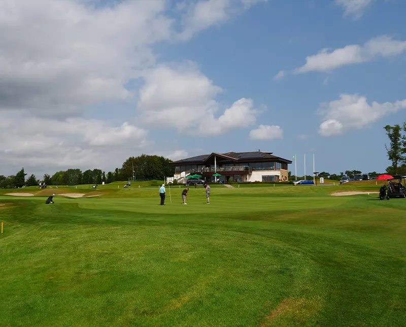 Golfers playing in front of clubhouse